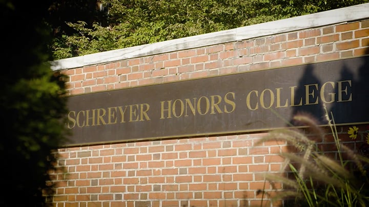 Brick wall with a sign that reads Schreyer Honors College.